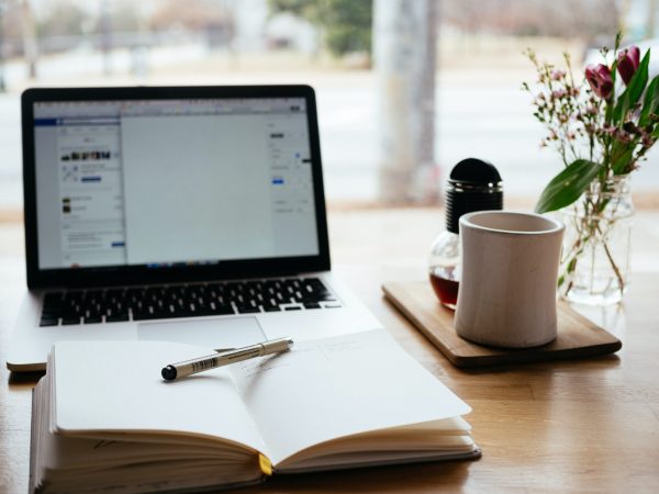 Laptop, notepad, and coffee mug on a table