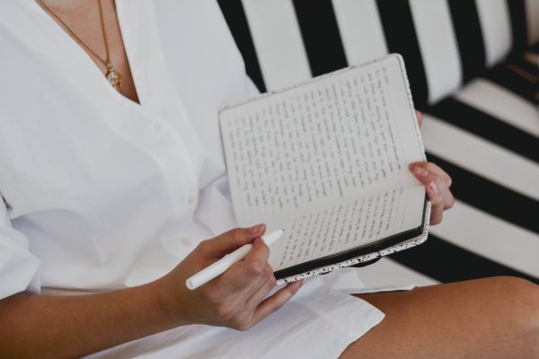 Woman writing in journal on black and white couch.