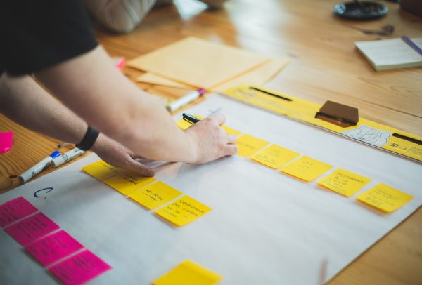 man adding sticky notes to a large piece of white paper